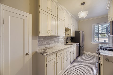 A kitchen with white cabinets and a black refrigerator.